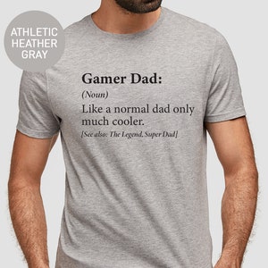 May include: A gray t-shirt with the text "Gamer Dad: (Noun) Like a normal dad only much cooler. [See also: The Legend, Super Dad]" printed on the front.