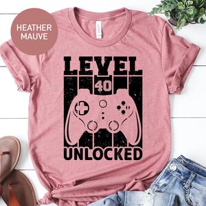 May include: Heather mauve t-shirt with a black graphic of a video game controller and the text "LEVEL 40 UNLOCKED".