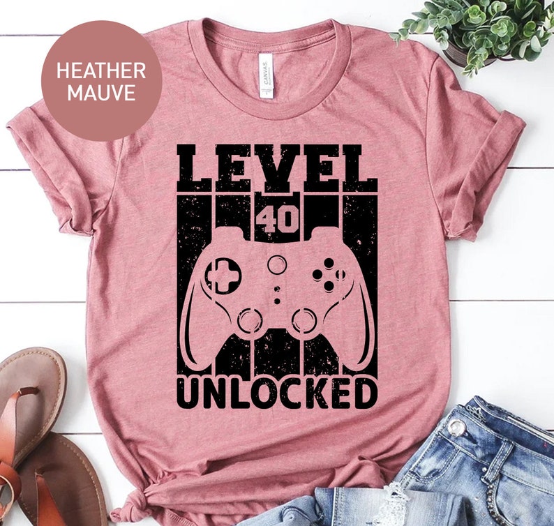 May include: Heather mauve t-shirt with a black graphic of a video game controller and the text "LEVEL 40 UNLOCKED".