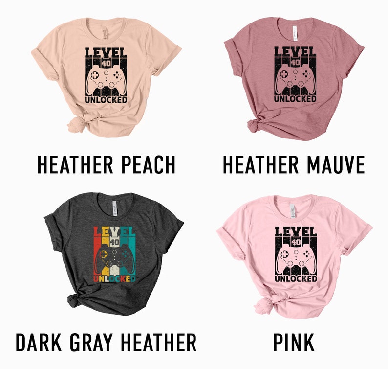 May include: Four different color t-shirts with a retro video game controller graphic and the text "Level 40 Unlocked". The colors are heather peach, heather mauve, dark gray heather, and pink.