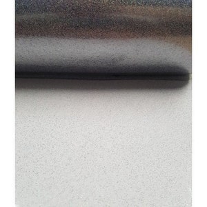 Puede incluir: Un rollo de papel de purpurina blanco con un brillo iridiscente plateado. El papel está texturizado con purpurina fina.