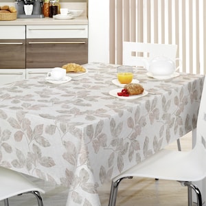 Puede incluir: Un mantel blanco con un estampado repetido de hojas marrones y grises cubre una mesa puesta para el desayuno. Sillas blancas con patas cromadas rodean la mesa. Hay una tetera, zumo y bollería.