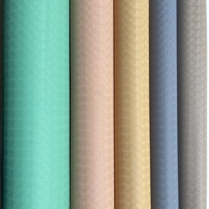 Könnte beinhalten: Fünf Rollen Tischdecken in verschiedenen Farben: hellgrün, beige, gold, grau und dunkelgrau. Jede Tischdecke hat ein sechseckiges Muster.