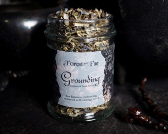May include: A glass jar filled with dried herbs labeled "of Forest and Fae Grounding spellwork herb blend" for balance, centering, sense of self, energy work.