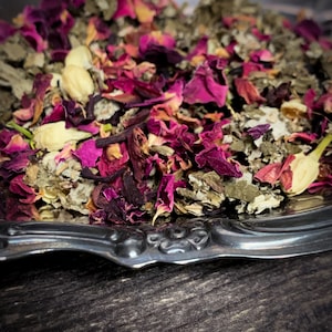 K&ouml;nnte beinhalten: Eine silberne Servierplatte gef&uuml;llt mit einer Mischung aus getrockneten Kr&auml;utern und Rosenbl&uuml;ten. Die Mischung ist hellrosa und gr&uuml;n.