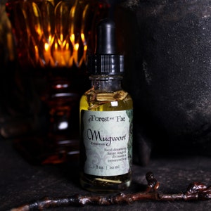 Puede incluir: Una peque&ntilde;a botella de vidrio con un gotero negro en la parte superior, llena de un l&iacute;quido amarillo y hierbas secas. La etiqueta dice "of Forest and Fae Mugwort dream oil lucid dreaming lunar magick divination consecration 1 fl oz | 30 ml".