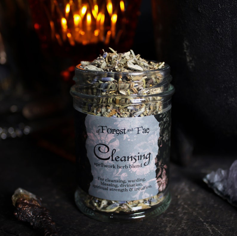 May include: A glass jar filled with dried herbs labeled "of Forest and Fae Cleansing spellwork herb blend" for cleansing, warding, blessing, divination, spiritual strength & intuition.