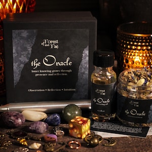 Pode incluir: Uma caixa preta rotulada Forest of and Fae the Oracle com um frasco de óleo de unção e um pote de ervas secas. O conjunto inclui um dado de seis lados, várias pedras polidas, uma haste prateada e pequenos pingentes de metal.