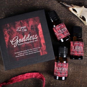 May include: A black box set labeled "Goddess home fragrance set" with three small amber glass bottles of home fragrance oil. The bottles are labeled "The Morrigan", "Lilith", and "Inanna". The set includes a red ribbon.