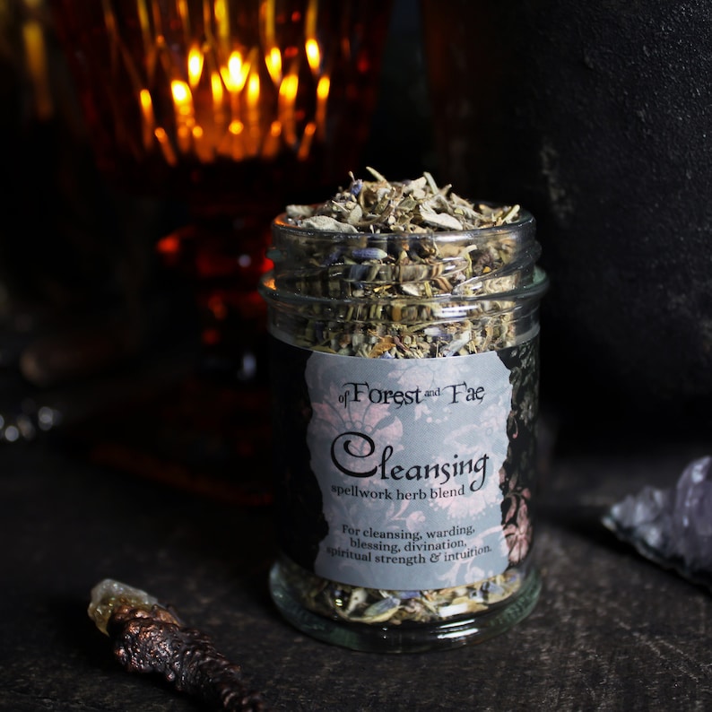 May include: A glass jar filled with dried herbs labeled "of Forest and Fae Cleansing spellwork herb blend" for cleansing, warding, blessing, divination, spiritual strength & intuition.