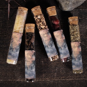 Puede incluir: Seis viales de vidrio con tapones de corcho, cada uno lleno de diferentes hierbas y resinas secas. Los viales tienen etiquetas con texto que incluye "Pine Resin", "Calamus Root" y "Rose Hips". Están dispuestos sobre una superficie de madera oscura.