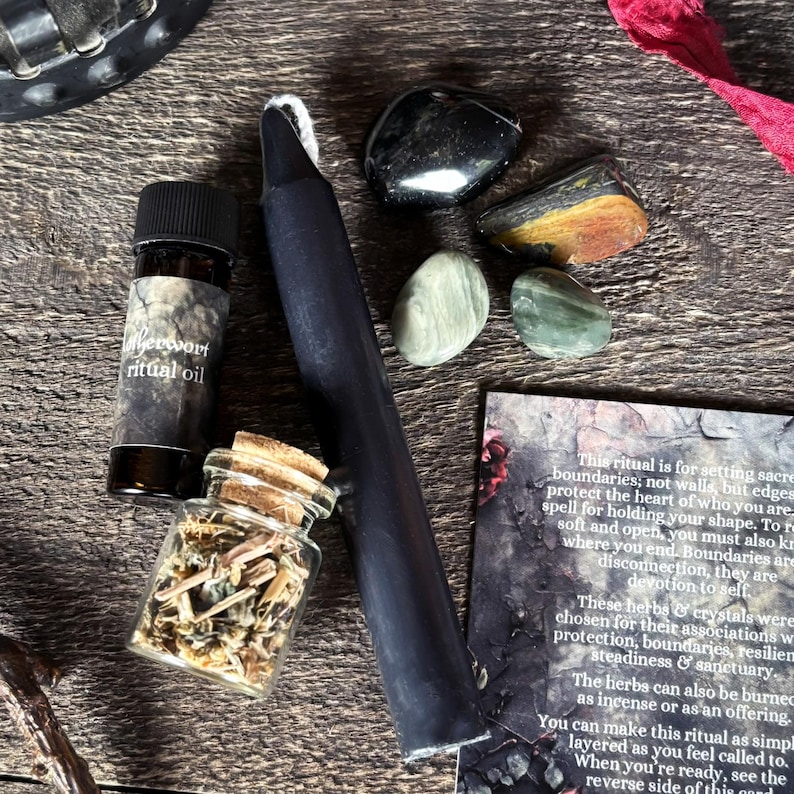 K&ouml;nnte beinhalten: Eine Sammlung spiritueller Gegenst&auml;nde, darunter eine schwarze Kerze, Kristalle, eine kleine Flasche Ritual&ouml;l und ein Glasgef&auml;&szlig; mit Kr&auml;utern. Die Gegenst&auml;nde sind auf einer Holzoberfl&auml;che angeordnet, mit einer Karte mit Text &uuml;ber Rituale.