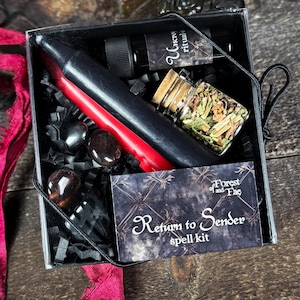 May include: A black box with a red candle, black stones, a small bottle of oil, a small jar of herbs, and a card that says "Return to Sender spell kit" with the text "Forest of and Fae" above it.