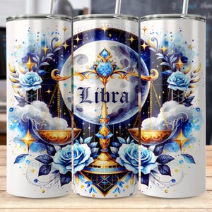 May include: White tumbler featuring a Libra zodiac design. The design includes a full moon, scales, blue roses, and celestial elements in shades of blue, gold, and white. The word "Libra" is prominently displayed.