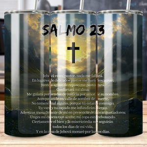Może przedstawiać: Kubek ze stali nierdzewnej ze słomką, z napisem "SALMO 23" i krzyżem na tle krajobrazu. Kubek ma pismo w języku hiszpańskim. Tło przedstawia zachód słońca nad górami.