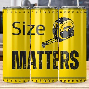 Könnte beinhalten: Ein gelber Becher mit einer schwarzen Maßbandgrafik und dem Text "Size Matters". Der Becher hat ein schwarzes Lineal auf dem Boden.