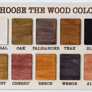 Pu&ograve; includere: Una tabella colori in legno con la scritta "CHOOSE THE WOOD COLOR" in alto. La tabella mostra 10 campioni di legno rettangolari in vari colori, tra cui naturale, rovere, palissandro, teak e nero.