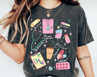 May include: Dark gray t-shirt with a colorful medical-themed graphic. The design includes a nurse's uniform, stethoscope, chart, coffee cup, pills, and other medical elements. The words "Nurse uniform" and other medical terms are also included.