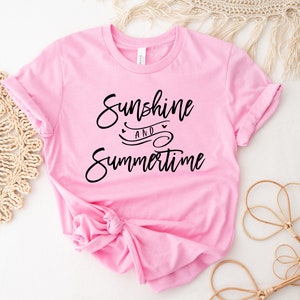 May include: Pink t-shirt with the text "Sunshine and Summertime" in black script font.