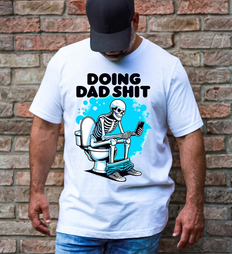 May include: White t-shirt with a skeleton sitting on a toilet and holding a phone. The text "Doing Dad Shit" is printed on the shirt.