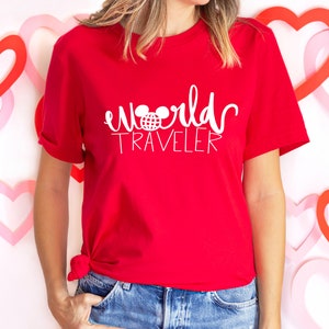 May include: Red t-shirt with white text that says "world traveler" and a white Mickey Mouse head with a globe inside the ears.