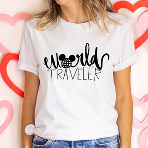 May include: White t-shirt with black text that reads "world traveler" with a Mickey Mouse head and globe graphic.