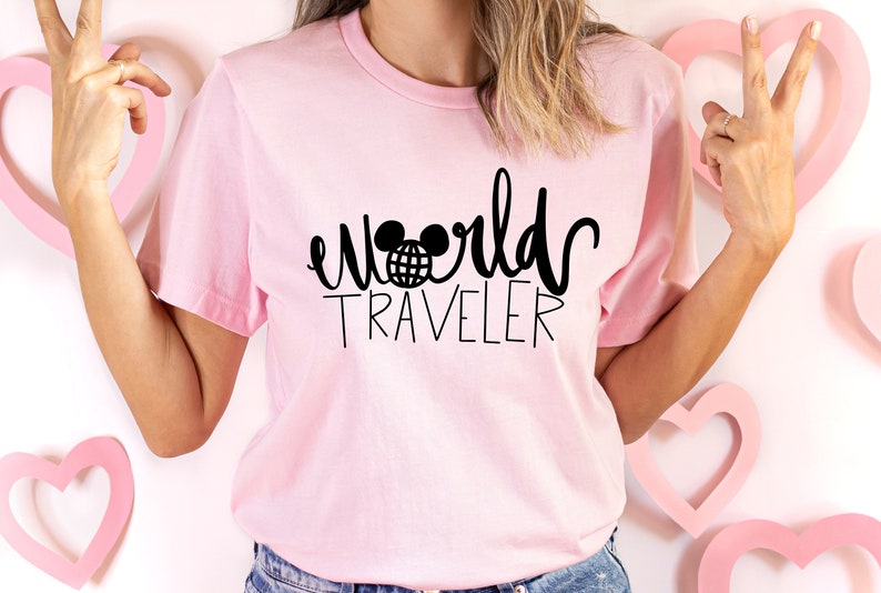 May include: Pink t-shirt with black text that says "world traveler" with a Mickey Mouse head and globe graphic.