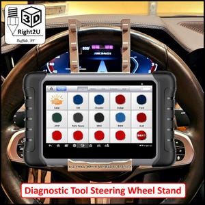 Könnte beinhalten: Ein schwarzes und graues Diagnose-Tablet, das auf einem Lenkradständer montiert ist. Der Tablet-Bildschirm zeigt ein Menü mit verschiedenen Automarken, darunter Ford, Audi, BMW und Jeep. Der Text "USE ONLY WHEN VEHICLE IS PARKED" ist auf dem Bildschirm sichtbar.