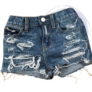 May include: Distressed denim shorts with frayed edges and multiple rips throughout the fabric. The shorts are a light blue wash and have a classic five-pocket design.