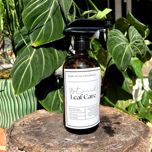 May include: A brown glass spray bottle with a black trigger nozzle and a white label reading Shade of Gray Greenhouse Botanical Leaf Care, Neem-infused Foliage Cleaner and Conditioner, Gentle Leaf Care, 16 oz (473ml) and descriptive text.