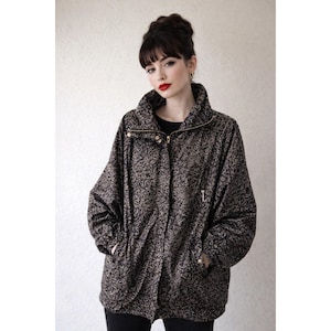 May include: A patterned jacket in shades of brown and black, featuring a high collar and a gold zipper. The jacket has two front pockets and a relaxed fit, suitable for casual wear.