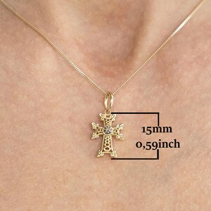 May include: Gold chain necklace with a detailed gold cross pendant featuring a small clear stone in the centre. The cross measures 15mm in diameter.