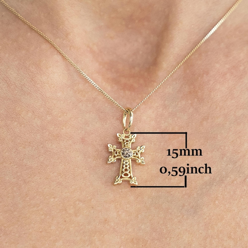 May include: Gold chain necklace with a detailed gold cross pendant featuring a small clear stone in the centre. The cross measures 15mm in diameter.