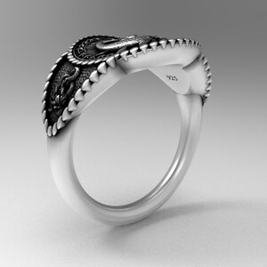 May include: A silver ring with a detailed design featuring a dragon and a crown. The ring is marked with "925" on the side.