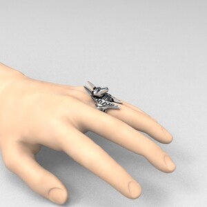K&ouml;nnte beinhalten: Ein silberner Ring mit einem detaillierten Anubis-Kopfdesign. Der Ring wird an einem Finger getragen.