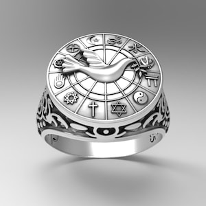 Op de afbeelding: Een zilveren ring met een duif en symbolen van verschillende religies rond de rand. De ring is gegraveerd met het nummer "745" aan de ene kant en "5" aan de andere kant.