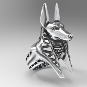 K&ouml;nnte beinhalten: Silberring mit einem detaillierten Anubis-Kopf mit einem geometrischen Muster am Kragen. Der Ring ist mit einem breiten Band gestaltet.