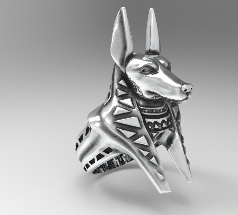 K&ouml;nnte beinhalten: Silberring mit einem detaillierten Anubis-Kopf mit einem geometrischen Muster am Kragen. Der Ring ist mit einem breiten Band gestaltet.