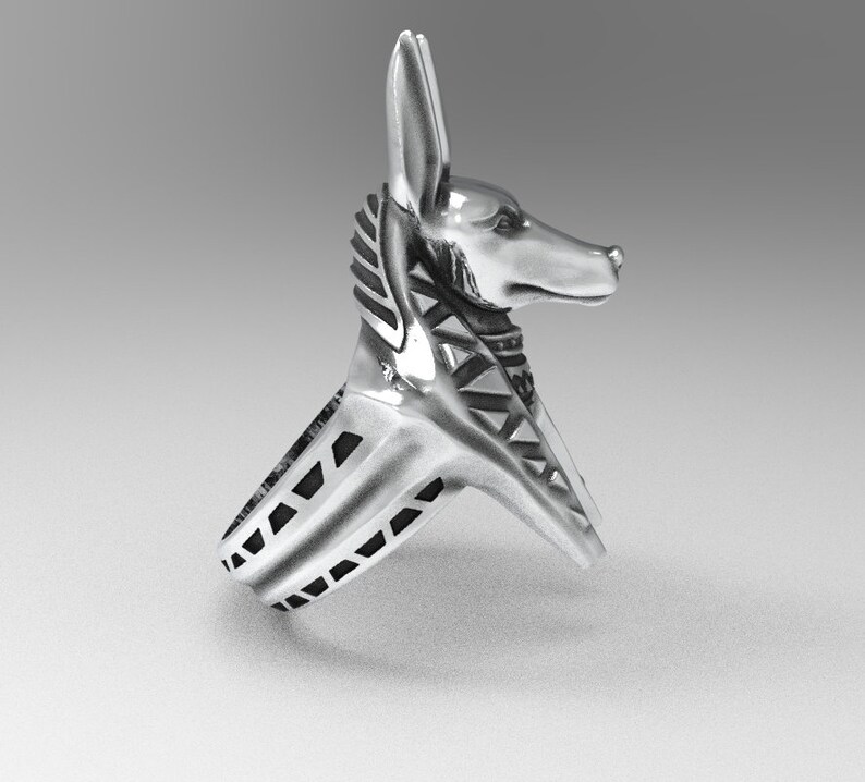 K&ouml;nnte beinhalten: Silberring mit einem Anubis-Kopfdesign. Der Ringband ist mit schwarzen Akzenten strukturiert.