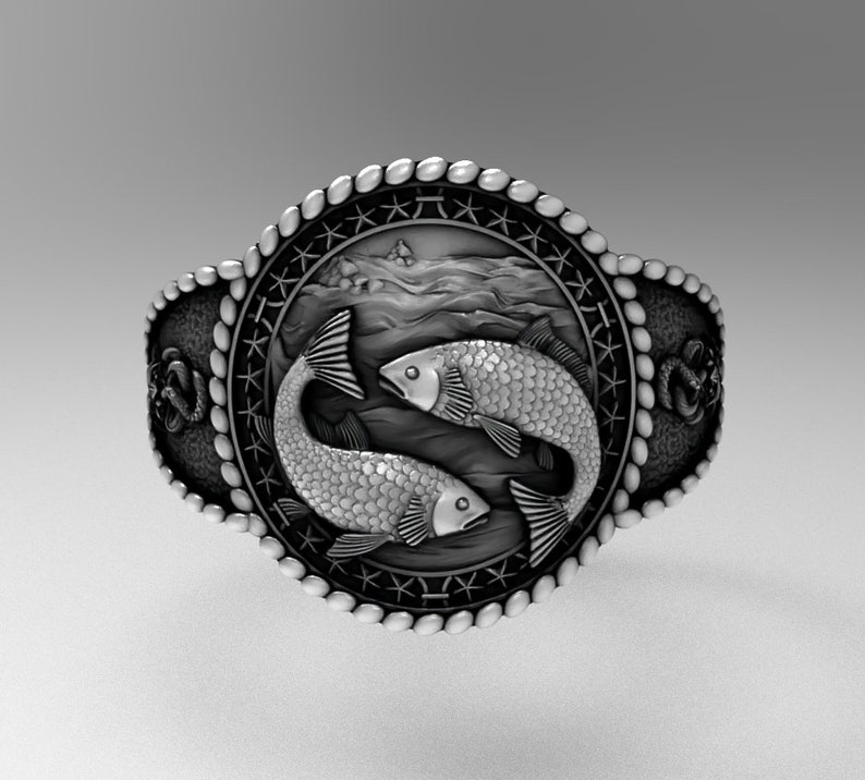 May include: A silver ring with a detailed design of two fish swimming in a wave pattern. The ring is surrounded by a rope-like border with stars.