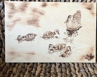 Pyrography engraved duck and ducklings on plywood in frame.