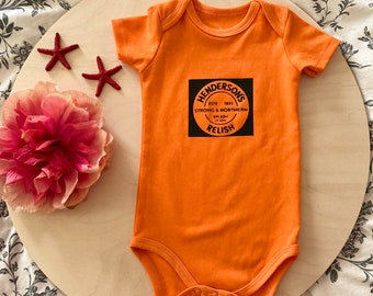 Hand printed orange vinyl baby vest inspired by Henderson’s Relish