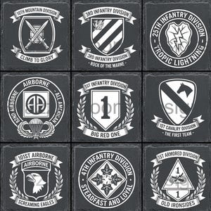 Op de afbeelding: Negen vierkante leistenen onderzetters met witte emblemen van militaire divisies op een donkere grijze achtergrond. Elke onderzetter toont een ander embleem, waaronder de 25e Infanteriedivisie.