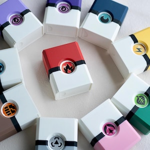 May include: A collection of colorful, rectangular boxes with various symbols and designs. Each box features a different color on the top and bottom, with a white center section. The boxes are arranged in a circular pattern.