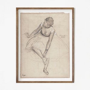 K&ouml;nnte beinhalten: Eine Schwarzwei&szlig;-Bleistiftzeichnung einer Ballerina in einem Tutu, die auf einer B&uuml;hne sitzt. Die Zeichnung ist in einem hellbraunen Holzrahmen gerahmt.
