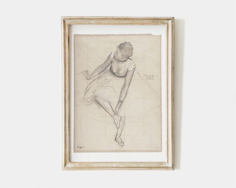 K&ouml;nnte beinhalten: Eine gerahmte Schwarzwei&szlig;-Bleistiftzeichnung einer Ballerina in einem Tutu, die sitzt und ihren Schuh anpasst. Die Zeichnung befindet sich auf einem karierten Hintergrund mit der Unterschrift des K&uuml;nstlers unten links.