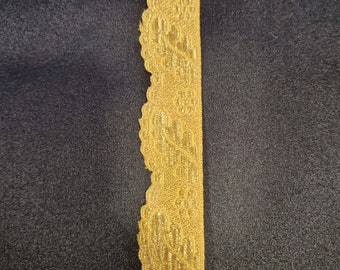 Pode incluir: Bordado de renda dourado com borda festonada e um padrão floral.