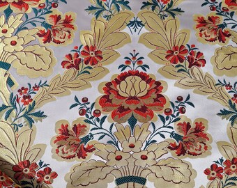 Puede incluir: Tela blanca con un patrón floral dorado, rojo y verde. La tela tiene una textura en relieve y un diseño damasco.