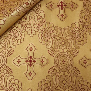 May include: Gold fabric with a red cross and floral pattern. The fabric has a raised texture.