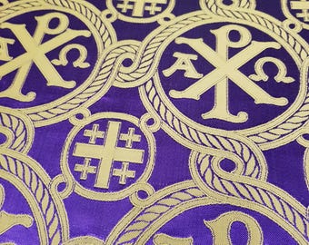 Puede incluir: Una tela de color morado con un patrón repetitivo bordado en hilo dorado que muestra símbolos Chi-Rho y cruces de Jerusalén. El diseño incluye bordes circulares entrelazados en forma de cuerda alrededor de cada Chi-Rho, creando un motivo denso.